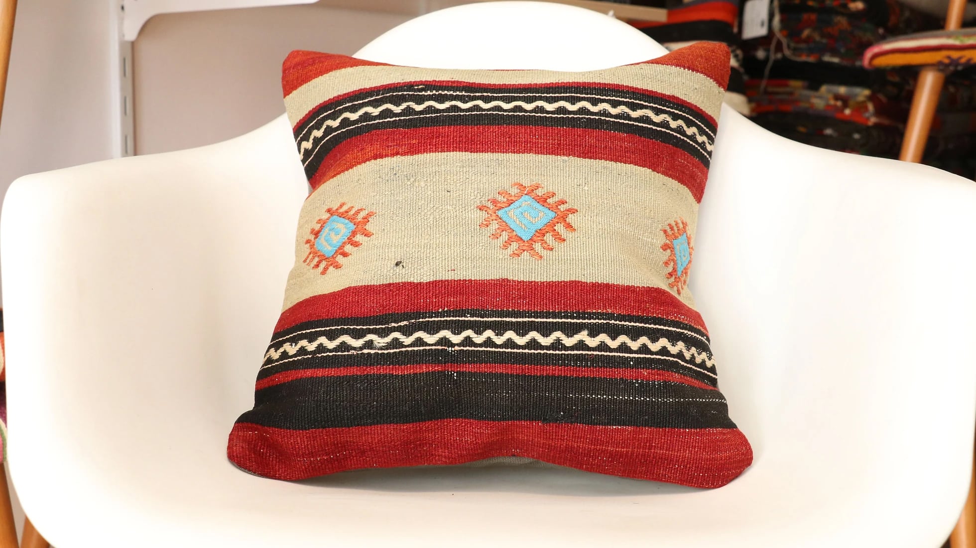vintage kilim covered pillow with blue diamond patterns in beige, black, and red