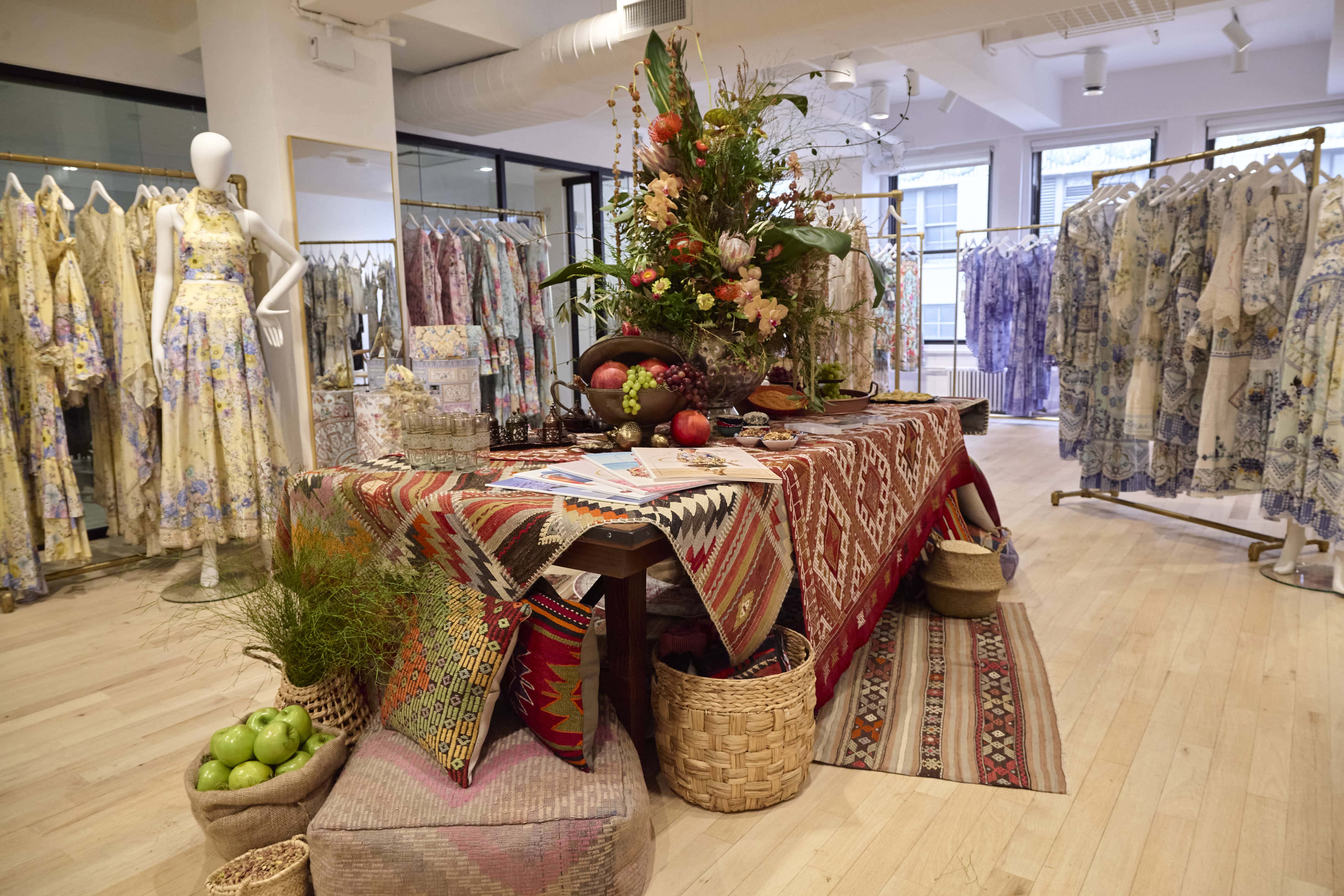 CAMILLA NYC press preview table styled with vintage Turkish kilims, kilim ottoman poufs and kilim pillows from Kilim Couture, featuring handwoven rugs, Ottoman poufs, kilim pillows, baklava, roasted nuts, and earth-toned glassware in a Turkish bazaar-inspired setting.