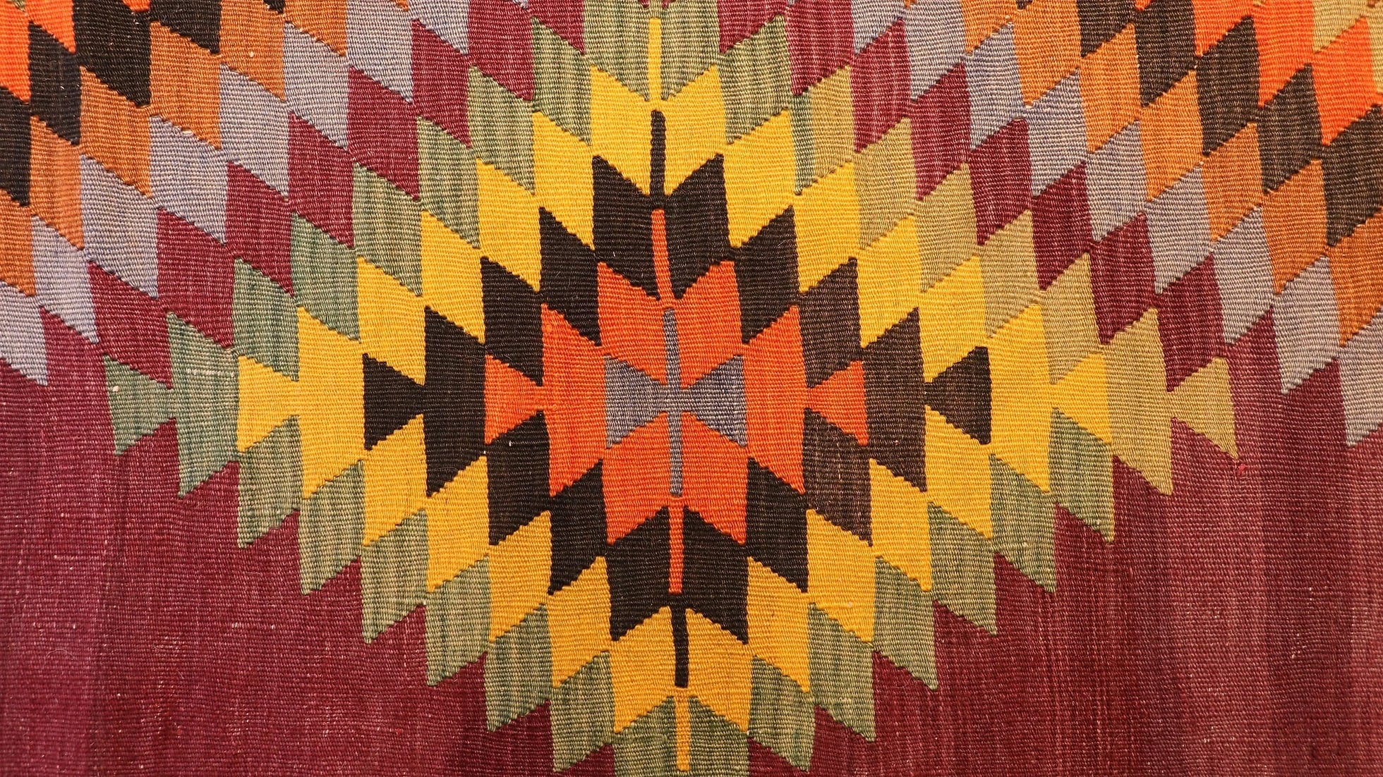 zoom in on the traditional lozenge motif in green, yellow, black, and orange of the vintage runner rug by Kilim Couture New York