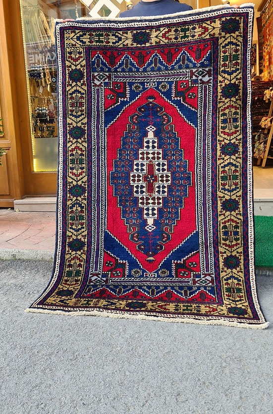 Hand-knotted in Taspinar, Turkey, this semi-antique 4x6 ft. rug features a striking medallion with intricate floral patterns in crimson, gold, and azure. Made from pure wool and dyed with natural pigments, it offers unmatched durability and elegance. Perfect for hallways, entryways, or kitchens, this rug blends Anatolian heritage with timeless design.