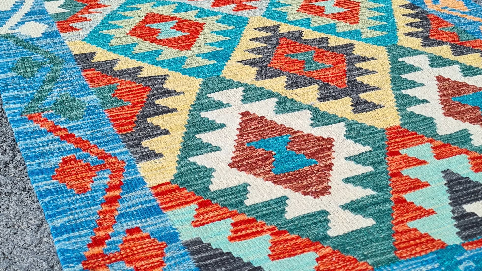 Close-up of a colorful geometric patterned rug with red, blue, and beige colors.