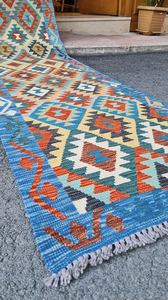 Close-up of a colorful geometric patterned rug with red, blue, and beige colors.