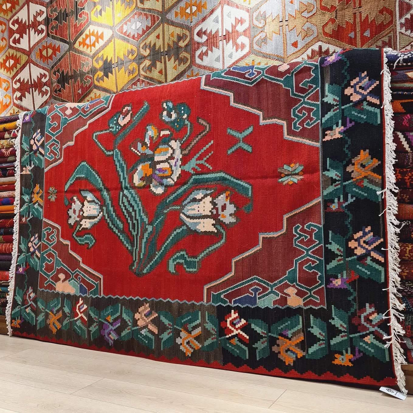 Handwoven vintage Bessarabian kilim rug, 5x7 ft, with a bold oriental red backdrop featuring intricate floral bouquets in cream, aqua green, purple, and lush green foliage, framed by a faded black border with floral accents, showcasing mid-20th century craftsmanship and European elegance.