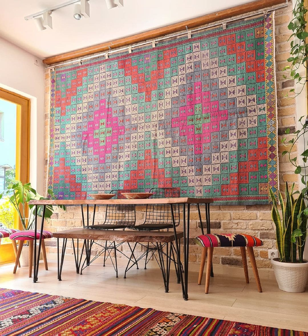 Vintage handwoven Cecim Kilim Rug with faded hues in pink, red and green on the wall