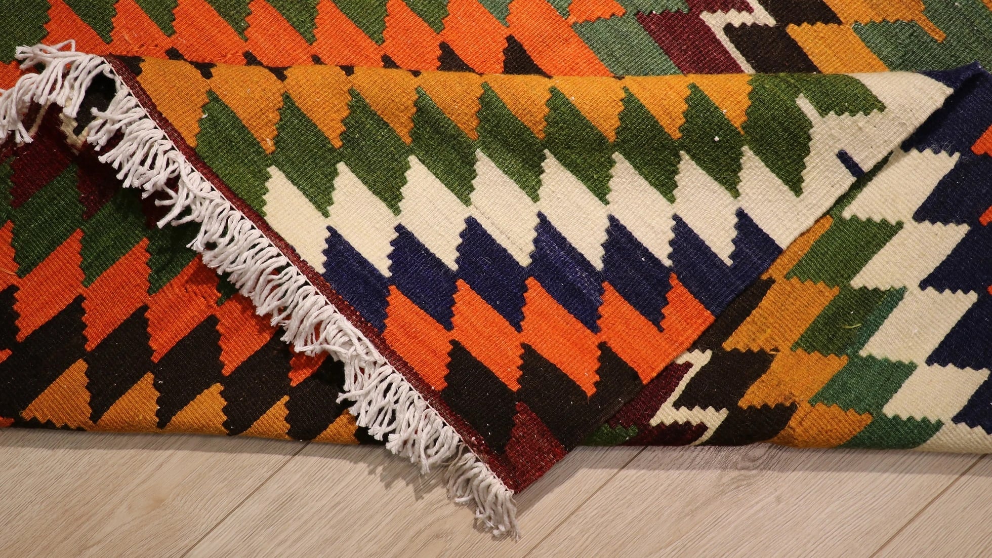 back of the Diamond patterned turkish kilim rug in orange with tassels in detail