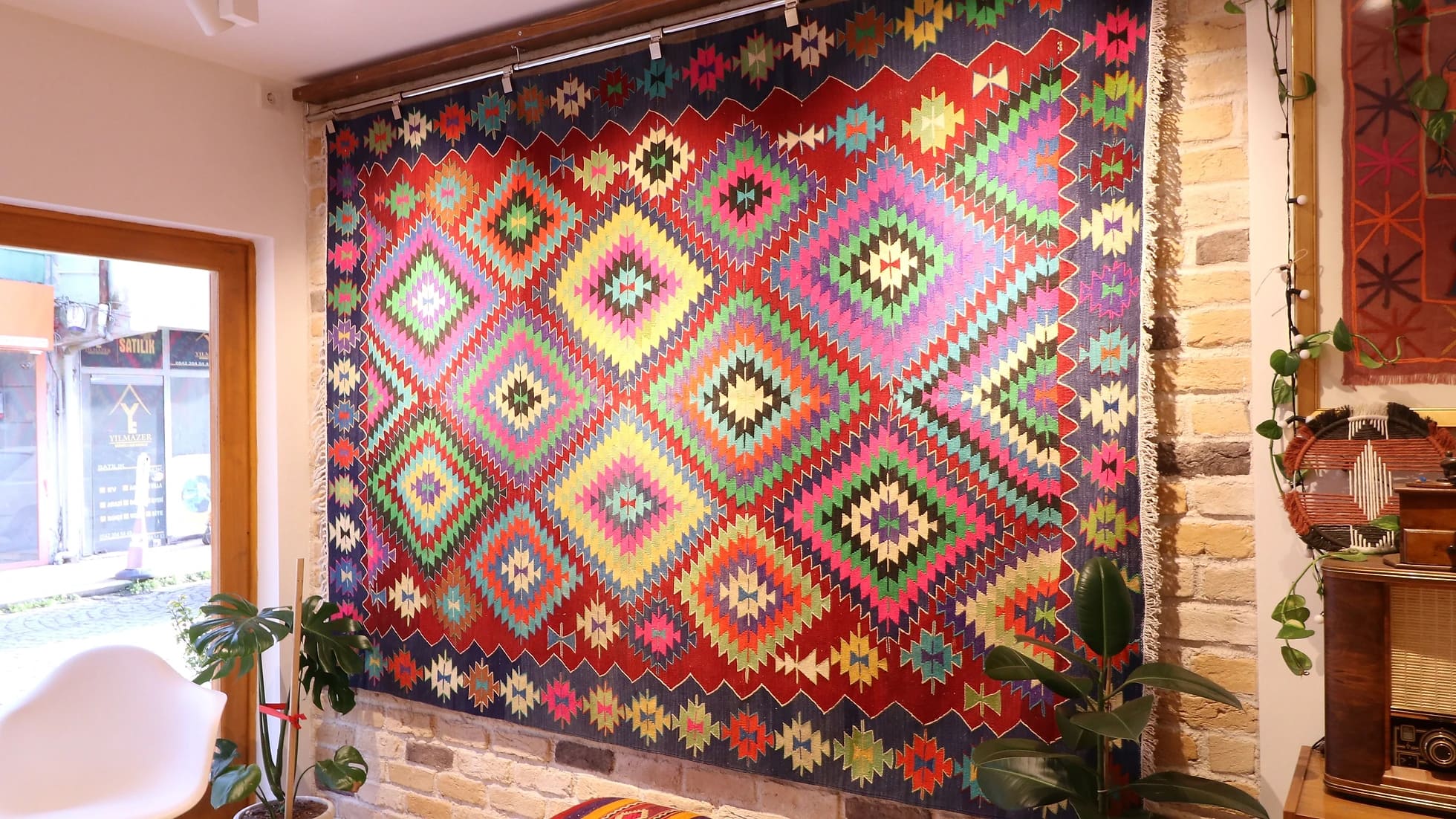 a magnificent and colorful large vintage rug from turkey in traditional motifs and modern style hanging on the wall like a quilt or tapestry