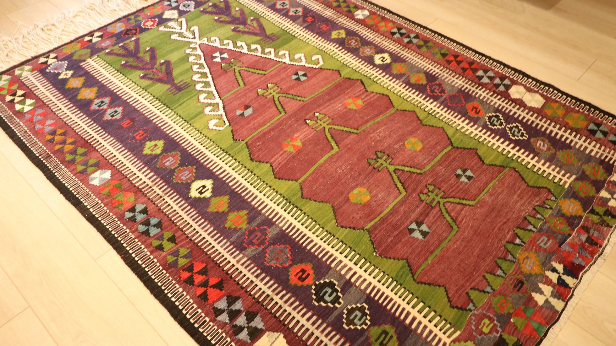medium-sized handwoven Konya prayer rug with long white fringes featuring many traditional motifs and rustic colors