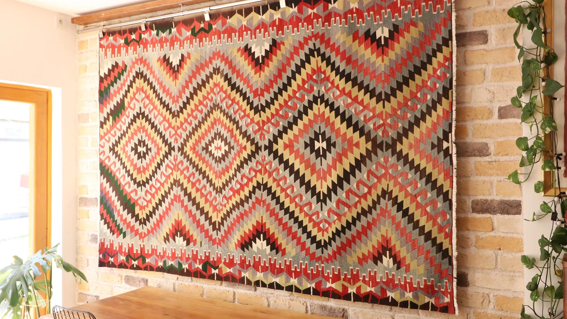 one-of-a-kind flat-woven Turkish rug in contemporary style with diamond and lozenge patterns in beige, red, and black hanging on the wall as a tapestry