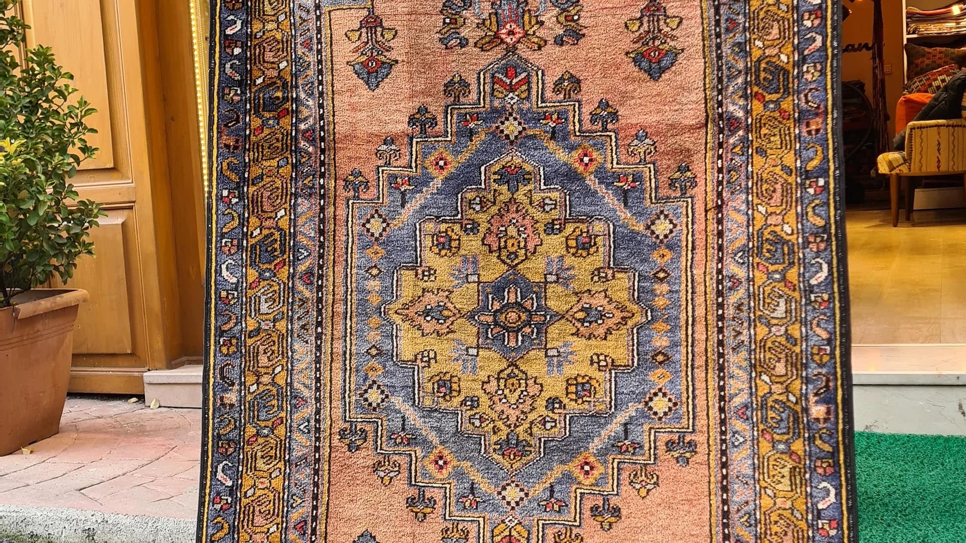 Mid-century Yahyali rug from Kayseri, Turkey, 3x7 ft, handwoven with 100% wool. Features a soft dusty peach background with a central floral medallion in powder blue and gold, surrounded by delicate floating motifs and a triple floral border. Crafted using natural dyes from madder root and walnut shells, showcasing traditional Turkish artistry and durable craftsmanship.