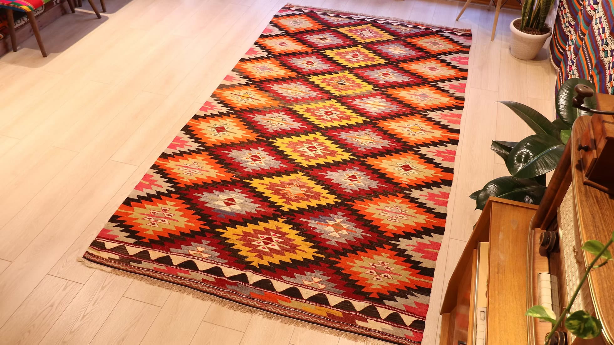 Wide shot of the Vintage Turkish Handwoven Afyon Ethnic Flat-Woven Rug in a modern living room setting with bold colors and craftsmanship