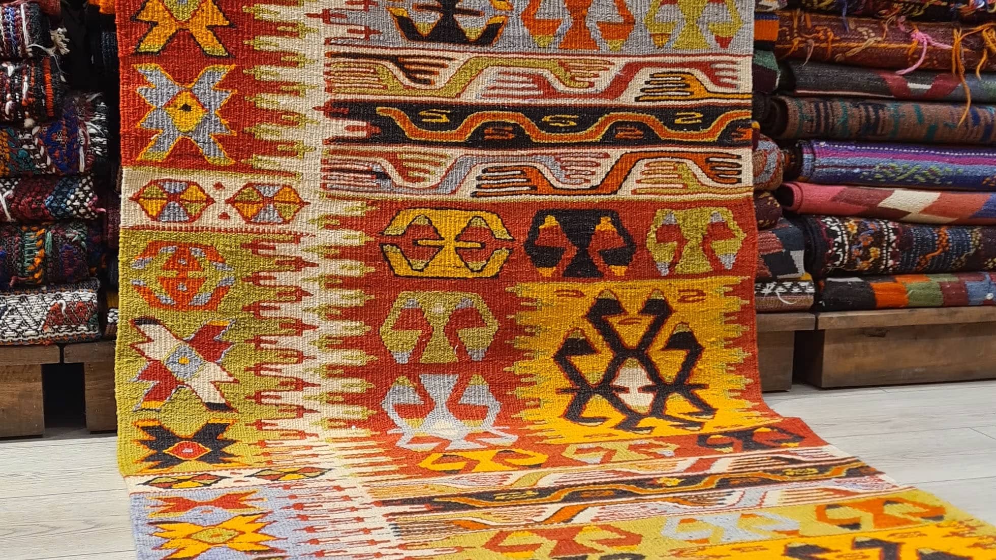 1940s handwoven kilim runner from Denizli, Turkey, showcasing ember red, golden saffron, and burnt umber hues with ancestral motifs like the wolf's mouth and fertility symbols