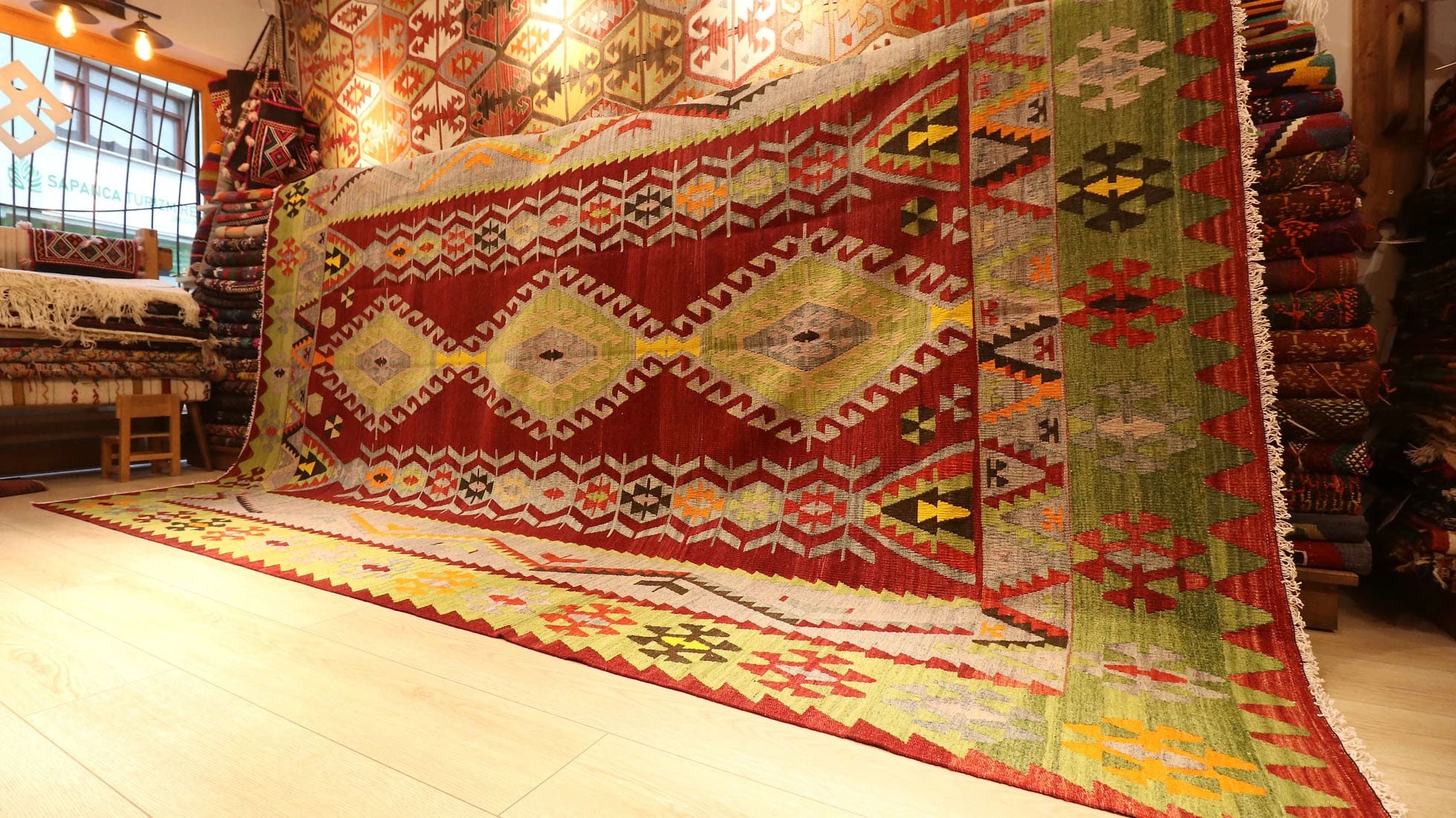 Vintage Turkish kilim runner rug from Fethiye, 8x11 ft, handwoven in the 1960s. Features vibrant lozenge motifs in pistachio, brick red, dove gray, yellow, and orange on a warm brick red background, framed by a double-layered border with intricate 'wolf's mouth' motifs. A rare and authentic piece of Turkish artistry.