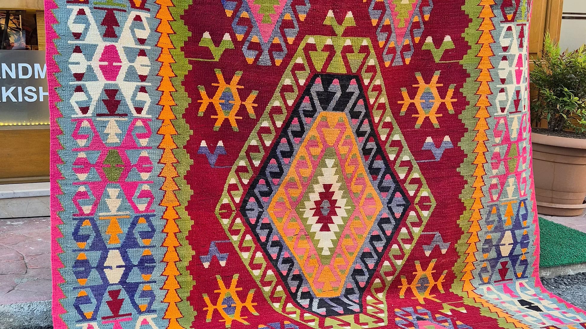Vintage Turkish kilim rug from Çal village, 1950s, featuring a large central dragon and four smaller dragons in fuchsia rose, olive green, and sapphire blue on a pomegranate red field, with traditional Anatolian fertility motifs and amber and moss running water patterns.