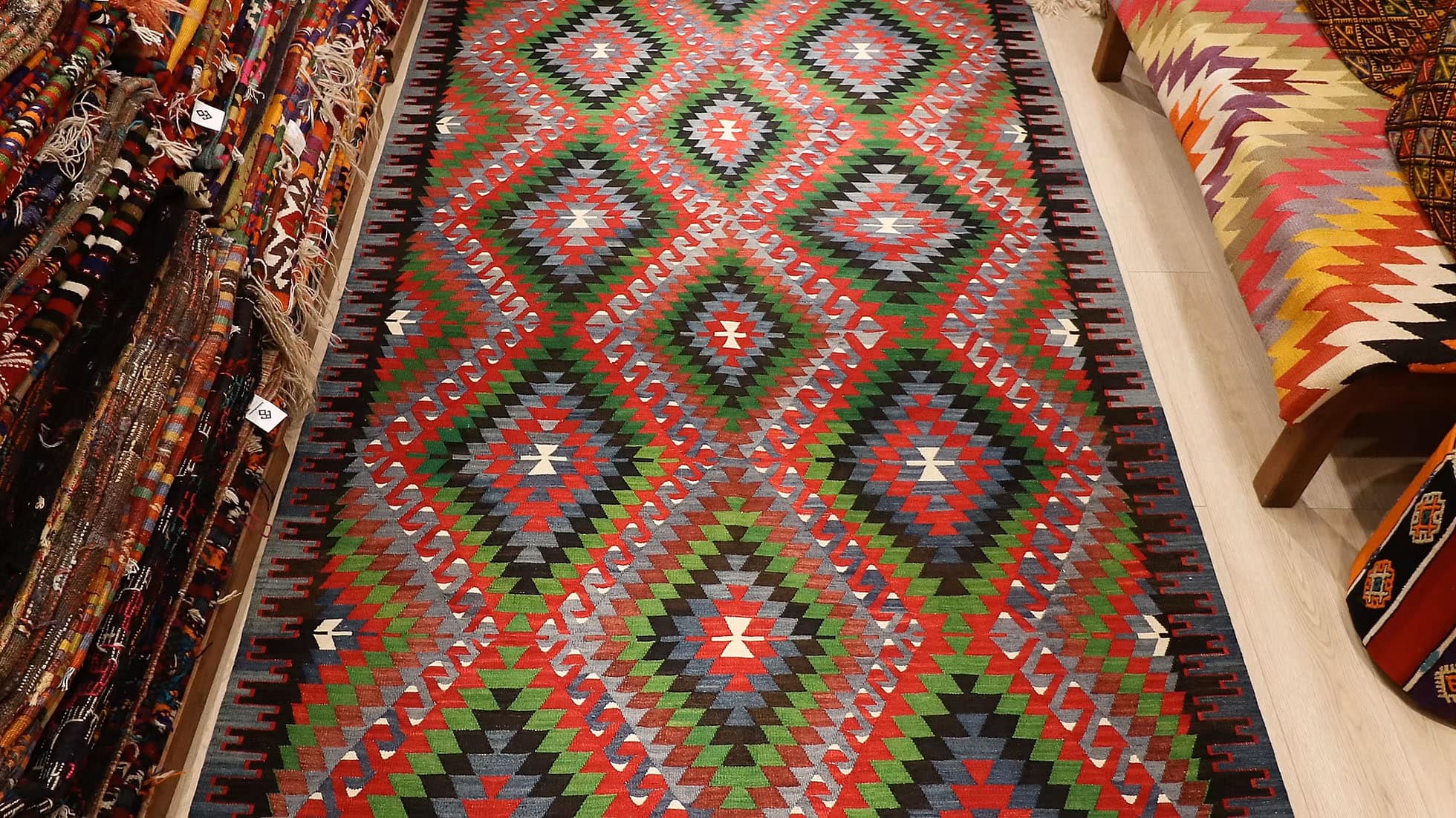 Vintage Turkish Denizli Kilim. This rare 1950s handwoven kilim from Denizli, Turkey, features a striking royal crimson backdrop with intricate 'comb' border motifs in onyx truffle and smoky gray. Measuring 6x10, its bold lozenge pattern embodies the rich craftsmanship of Anatolian weaving. A timeless fusion of history and elegance, this versatile heirloom rug adds warmth and sophistication to any space.