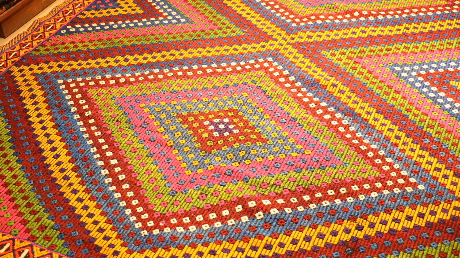 Vintage Soumak Flat-Woven Rug. Handwoven in Turkey circa 1950s, this 7x9 Soumak kilim showcases bold geometric patterns and a rich palette of burgundy, golden yellow, royal blue, and lush green. Featuring symbolic 'burdock' motifs and delicate tassels, this heirloom-quality wool rug bridges tradition with modern interiors, offering timeless artistry and lasting durability.