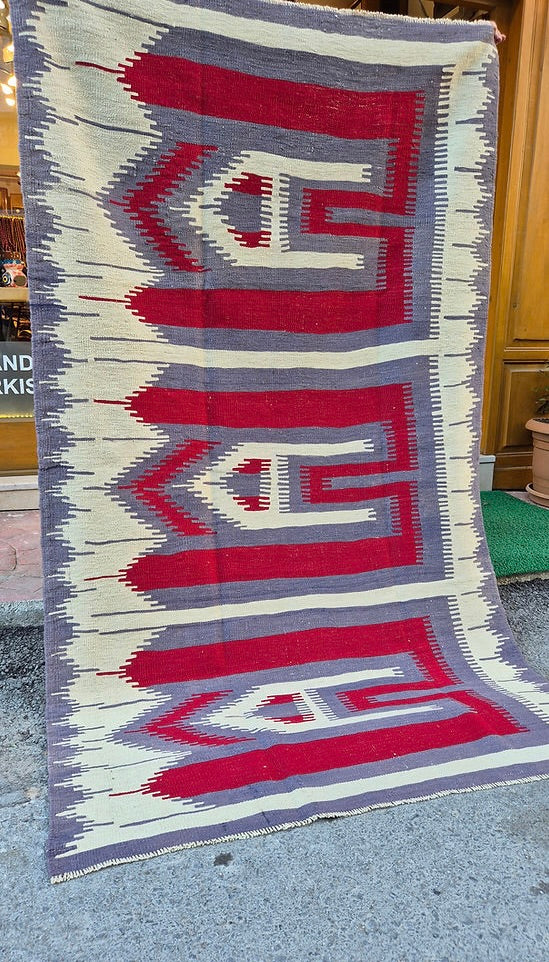 Vintage Turkish Usak rug featuring muted almond dust background and intricate comb motifs in stone gray and pomegranate.