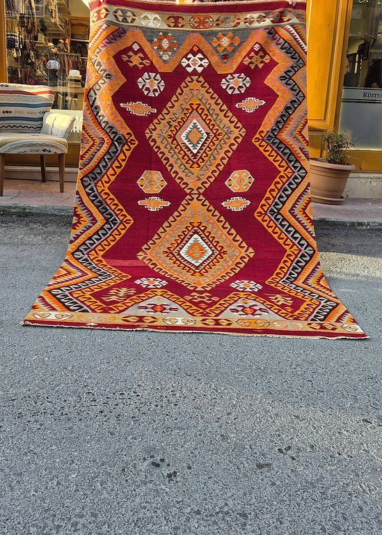 Mid-century flat-woven rug with bold diamond medallions and expressive tribal motifs in red and orange