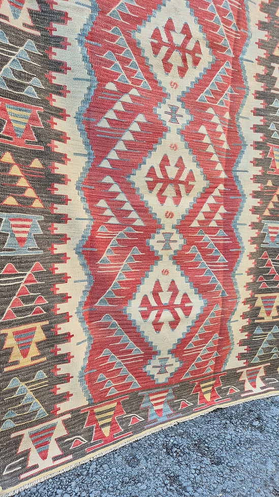 Close-up of a rustic patterned rug with geometric designs in red, beige, and blue by Kilim Couture New York Rug Gallery.