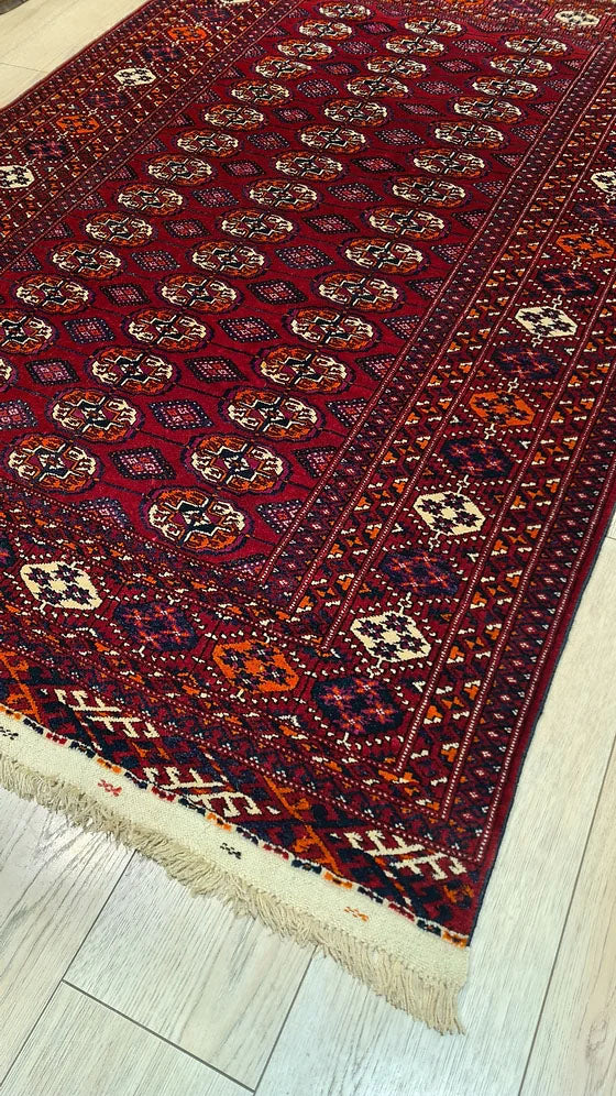 1960s Bokhara Oriental Rug – Classic Turkmen Handwoven Piece with geometric Gul Medallions and rich red hues, curated by Kilim Couture New York.