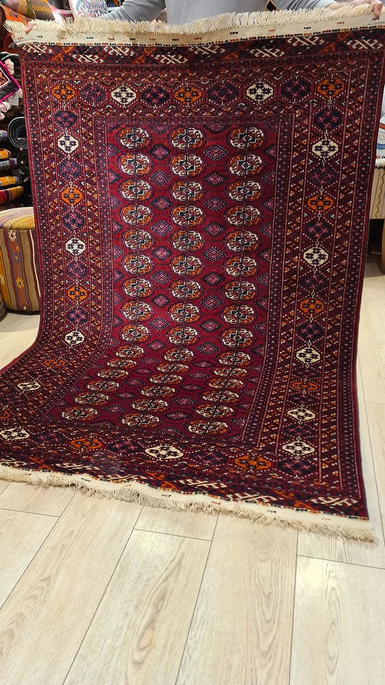 Vintage 1960s Turkmen Bokhara Rug – Handwoven with intricate Gul Medallion design and warm coral orange accents, featured in Kilim Couture New York rug gallery.